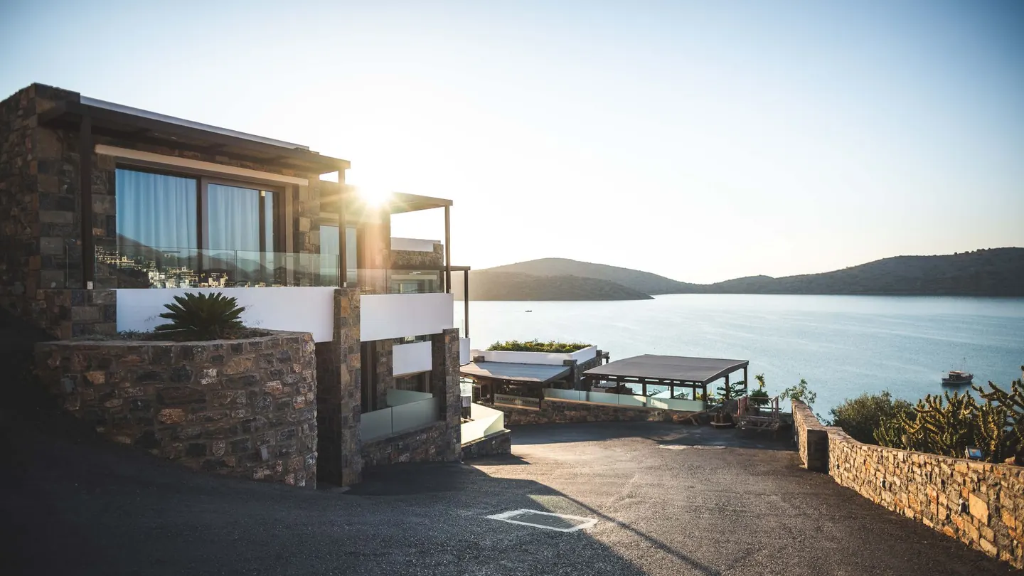 Modern hillside home overlooking water at golden hour