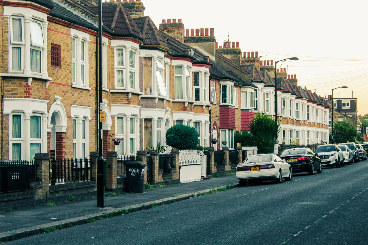 A row of London terraced houses with cars parked outside